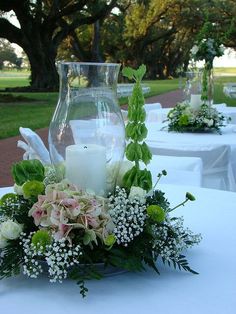 an arrangement of flowers and candles on a table at a wedding reception in the park