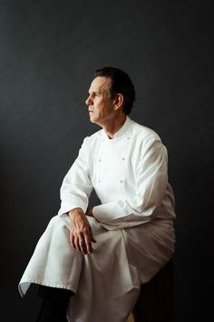 a man sitting on top of a wooden chair wearing a white shirt and black pants