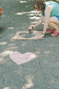 a woman kneeling down next to a heart cut out on the ground in front of a dog