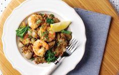 a white plate topped with shrimp and broccoli on top of a wooden table