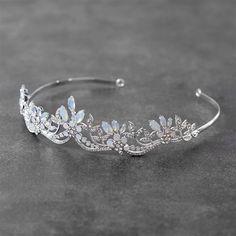 a tiara with crystal flowers and leaves on the headband is sitting on a gray surface