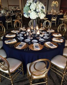 the table is set with gold and black plates, silverware, and white flowers