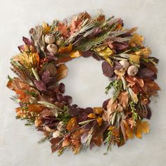 a wreath made out of dried leaves and other autumn foliages on a white background