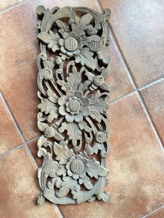 an intricately carved piece of wood sitting on the floor in front of a tile wall