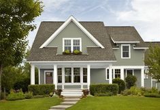 a gray house with white trim on the front door and steps leading up to it