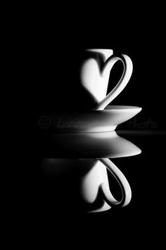 two coffee cups sitting next to each other on top of a black surface with reflections in the water