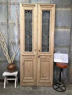 an old pair of doors sitting next to a small table with a sign on it