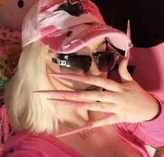 a woman in pink shirt and sunglasses holding her hands up to her face