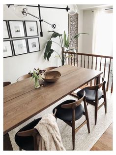 a wooden table with black chairs and pictures on the wall