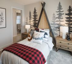 a bedroom decorated in black and white with trees on the wall