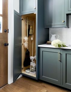 an open cabinet door in a kitchen with wooden flooring and blue painted cupboards