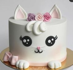 a white cake decorated with pink roses and cat ears