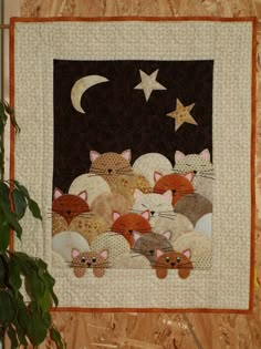 a quilted wall hanging with many cats on it and the moon in the background