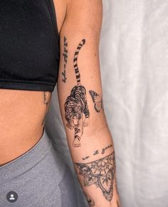 a woman's arm with tattoos on it and a tiger in the middle of her arm