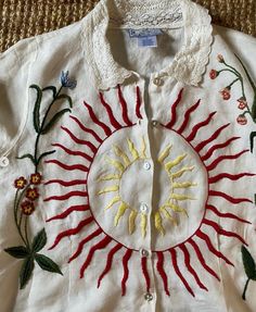 a white shirt with embroidered sun and flowers on it