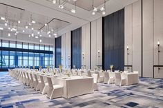 a banquet hall with tables and chairs set up for a formal function in front of large windows