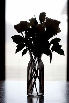 a vase filled with flowers sitting on top of a wooden table next to a window