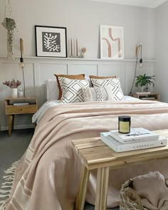 a bedroom with a bed, nightstands and pictures on the wall above it in neutral colors