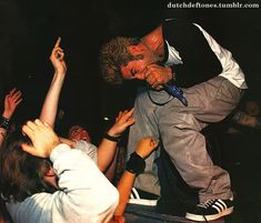 a group of people standing around one another with their hands in the air