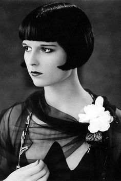 an old photo of a woman with short hair and a flower in her lapel