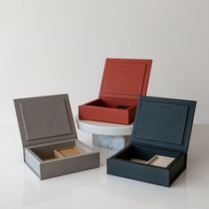 three open boxes sitting on top of a white table next to an empty box with a watch in it