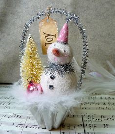 a snowman ornament sitting on top of a sheet with music notes in the background