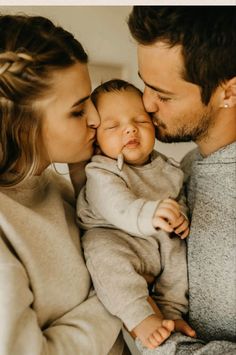 a man and woman are kissing their baby