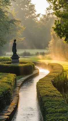 a small river running through a lush green park next to a statue in the middle of a garden