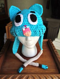 a blue crocheted hat with big eyes on top of a mannequin head