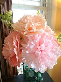 three large pink flowers in a vase on a table