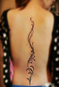 a woman's back with a tattoo design on her left side ribcage