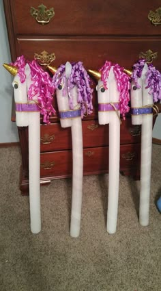 three unicorn - shaped candles are lined up on the floor in front of a dresser