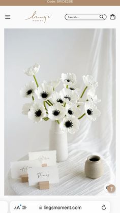 a white vase filled with lots of flowers on top of a table next to cards