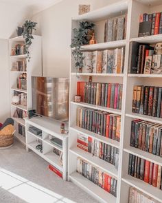 a living room filled with lots of books on top of white shelving unit units