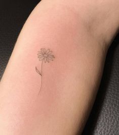 a small daisy tattoo on the arm