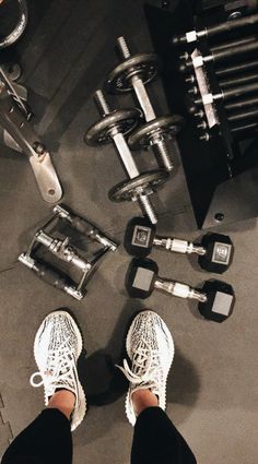 a person standing in front of some dumbs and exercise equipment with their feet on the ground