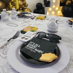 a table set for a baby shower with food and glasses on it, along with balloons in the background