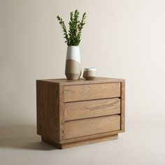 two vases on top of a wooden cabinet with plants in it and one is empty