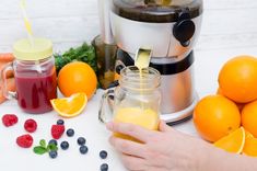 a person is pouring orange juice into a jar next to some fruit and veggies