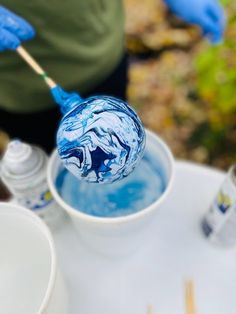 a person is holding a toothbrush in a cup filled with blue liquid and water