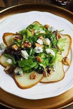 an apple salad with walnuts and feta cheese on a gold rimmed plate