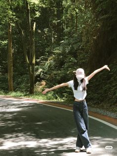 a woman is standing in the middle of a road with her arms spread out,