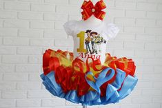 a birthday cake topper with the number one on it and red, blue, yellow and orange ruffles