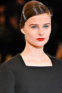 a woman with red lipstick on the runway