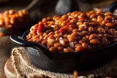 baked beans in a cast iron skillet on a wooden table with other food items