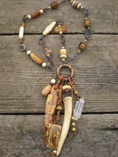 a necklace made out of beads and other items on a wooden table with a chain attached to it