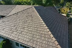 an aerial view of a house with a brown roof and green trees in the background