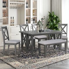 a dining table with four chairs and a bench in front of it on top of a rug