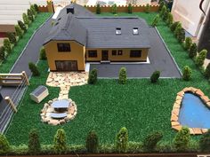 a model house is shown in the middle of a fake lawn and landscaping area with a pond