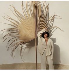 a woman standing next to a tall palm tree in the middle of a sandy area